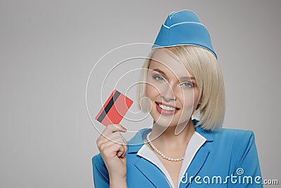 Smiling blonde stewardess holding credit card in her hand. Stock Photo