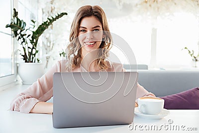 Smiling blondy woman in blouse sitting by the table Stock Photo