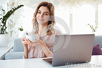 Smiling blondy woman in blouse sitting by the table Stock Photo