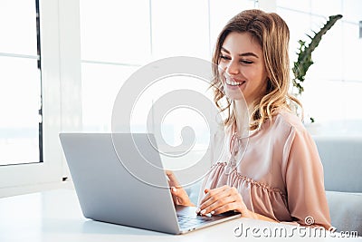 Smiling blondy woman in blouse sitting by the table Stock Photo