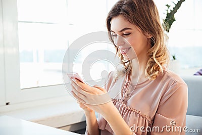 Smiling blondy woman in blouse sitting by the table Stock Photo