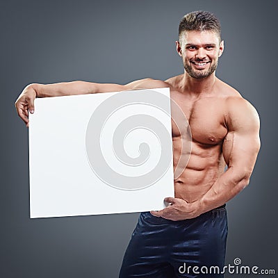 Smiling bodybuilder holding blank white poster Stock Photo