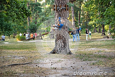 Smiling boy rides a zip line. happy child on the zip line. The kid passes the rope obstacle course Stock Photo