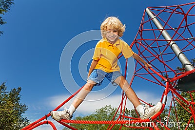 Smiling boy stands on red rope with legs apart Stock Photo