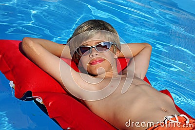 Smiling boy with sun glasses relaxing on airbed Stock Photo