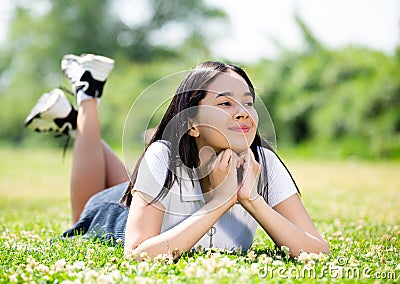Smiling brazilian teenager while lying in summer green park Stock Photo