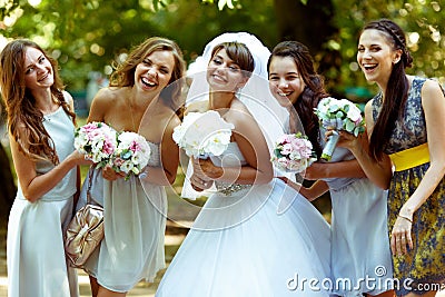 Smiling bride poses with happy bridesmaids with bouqets in their Stock Photo