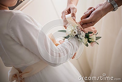 Smiling bridesmaid assists a young girl by securely fastening a flower corsage to her wrist Stock Photo