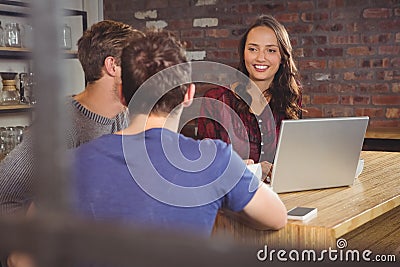 Smiling brunette using laptop and looking at her friends Stock Photo