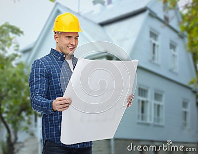 Smiling builder with blueprint over house Stock Photo