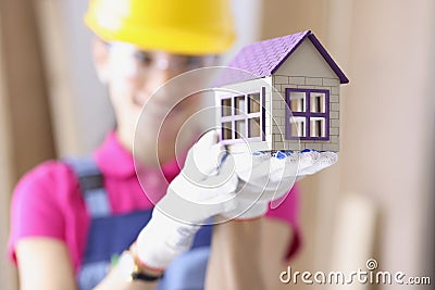 Smiling builder in hard hat holds miniature house Stock Photo