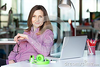 Smiling Business Lady in casual clothing sitting at Office Table Stock Photo