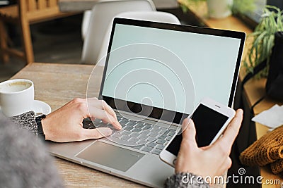 business man sitting at a table in a cafe with a laptop using a smartphone Stock Photo