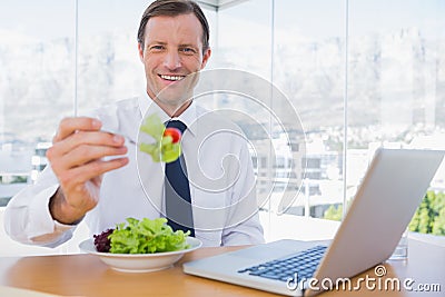 Smiling businessman eating a salad Stock Photo