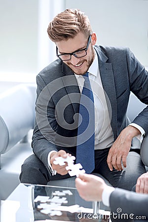 Smiling businessman helping the partner to complete the puzzle Stock Photo