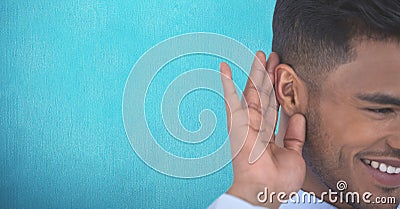 Smiling businessman listening gossip against colored background Stock Photo