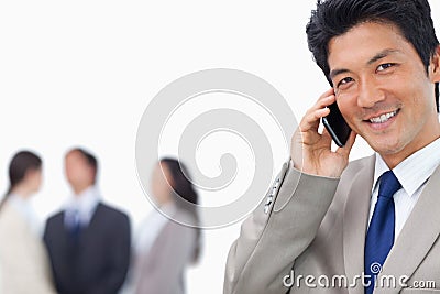 Smiling businessman on mobile phone and team Stock Photo