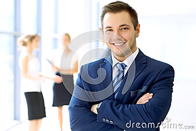 Smiling businessman in office with colleagues in the background Stock Photo