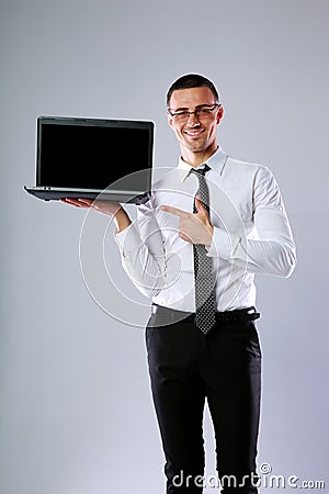 Smiling businessman standing with laptop Stock Photo