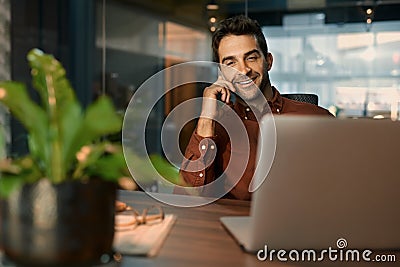 Smiling businessman talking on a cellphone while working late Stock Photo