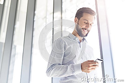 Smiling businessman texting on mobile phone at office Stock Photo