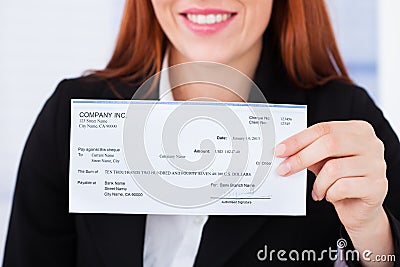 Smiling businesswoman holding cheque Stock Photo