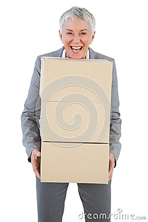 Smiling businesswoman holding heavy cardboard boxes Stock Photo