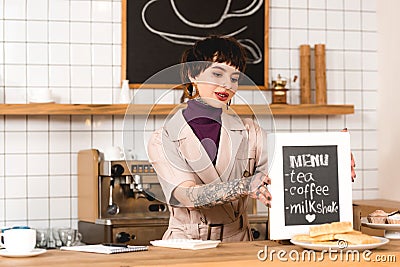 Smiling businesswoman placing menu board on bar counter in coffee shop. Stock Photo