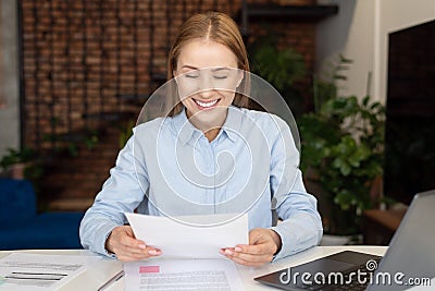 Smiling businesswoman reading documents when working at home Stock Photo