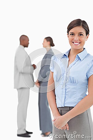 Smiling businesswoman with talking co-workers behind her Stock Photo