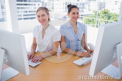Smiling businesswomen working side by side Stock Photo