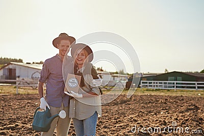 Smiling caucasian farmer couple on plowing field Stock Photo