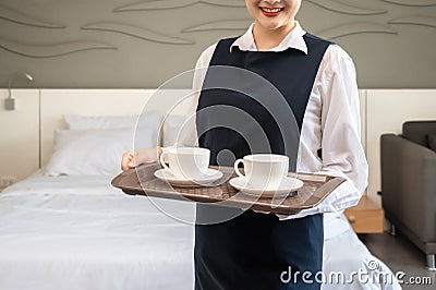 Smiling Chambermaid holding tray with cups of coffee. Hotel room service concept Stock Photo