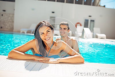 Smiling cheerful woman swimming in a clear pool on a sunny day.Having fun on vacation pool party.Friendly female enjoying relaxing Stock Photo