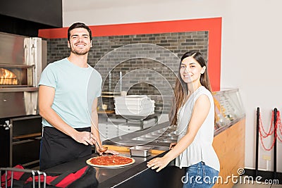 Smiling chef preparing customized pizza for customer Stock Photo