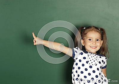 Smiling child girl show with a finger blank school blackboard, c Stock Photo