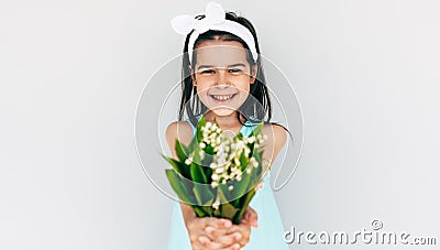 Smiling child holding the bouquet of white flowers giving it to her mother. Cute kid holding a bouquet in front of her face Stock Photo