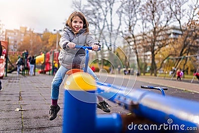 Smiling child on seesaw on the playground in the park Stock Photo