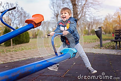 Smiling child on seesaw on the playground in the park Stock Photo