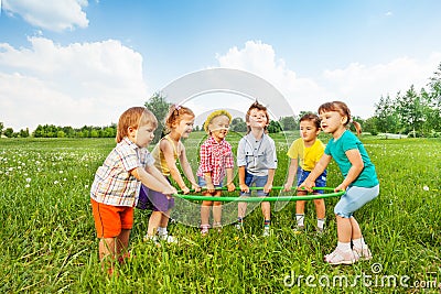 Smiling children holding one hoop together Stock Photo