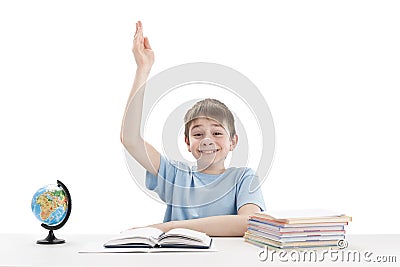 Smiling clever schoolboy raised his hand during the lesson. Excellent student knows the answer. Portrait of boy at the table Stock Photo