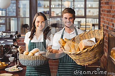 Smiling co-workers holding breads basket Stock Photo