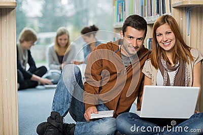 Smiling college students with laptop in library Stock Photo