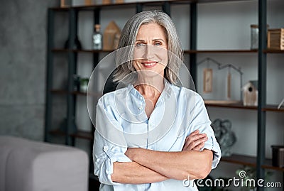 Smiling confident middle aged woman standing arms crossed in office, portrait. Stock Photo