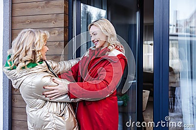 Joyful daughter welcoming her mother outside the cottage Stock Photo