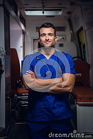 Smiling corpsman in blue medical uniform stands in the ambulance car Stock Photo