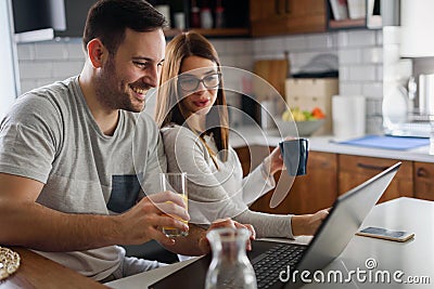 Smiling couple enjoying beautiful morning at home kitchen, starting to work from home in paj Stock Photo