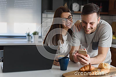 Smiling couple enjoying beautiful morning at home kitchen, starting to work from home in paj Stock Photo