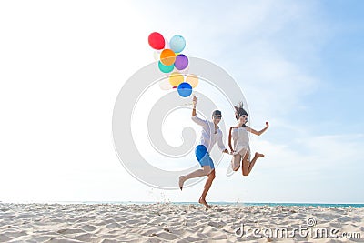 Smiling couple hand holding balloon and jumping together on the beach. Lover romantic and relax honeymoon in summer holiday. Summ Stock Photo