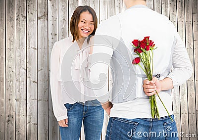 Smiling couple with man hiding roses in his back Stock Photo